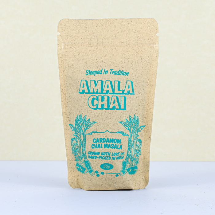 Kraft paper pouch of Amala Chai Cardamom Chai Masala with blue lettering and botanical illustrations.