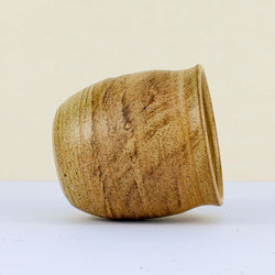 Side view of a handmade clay kulhar with a textured, earthy brown and beige swirl glaze, tilted slightly.
