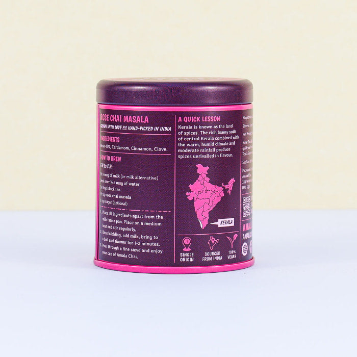 Side view of a magenta and dark purple tin of Amala Chai Rose Chai Masala showing ingredients, brewing instructions, and information about its origin in Kerala, India.
