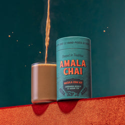 Masala Chai being poured into a cup from height next to a pack of Masala chai