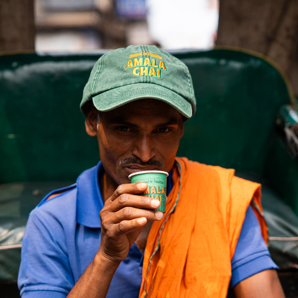 a man enjoying chai from an Amala Chai branded take-away cup, this shows how you may drink the product yourself. 