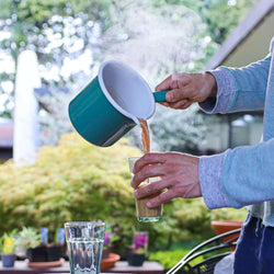 Enamel Chai Pan in action pouring chai into a cup